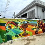 Colorful mural featuring an abstract eye and horse head with African tribal patterns and vibrant blue, orange, and yellow geometric background.